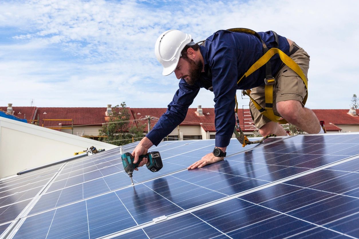 A man working on solar panels on the roof of a house.