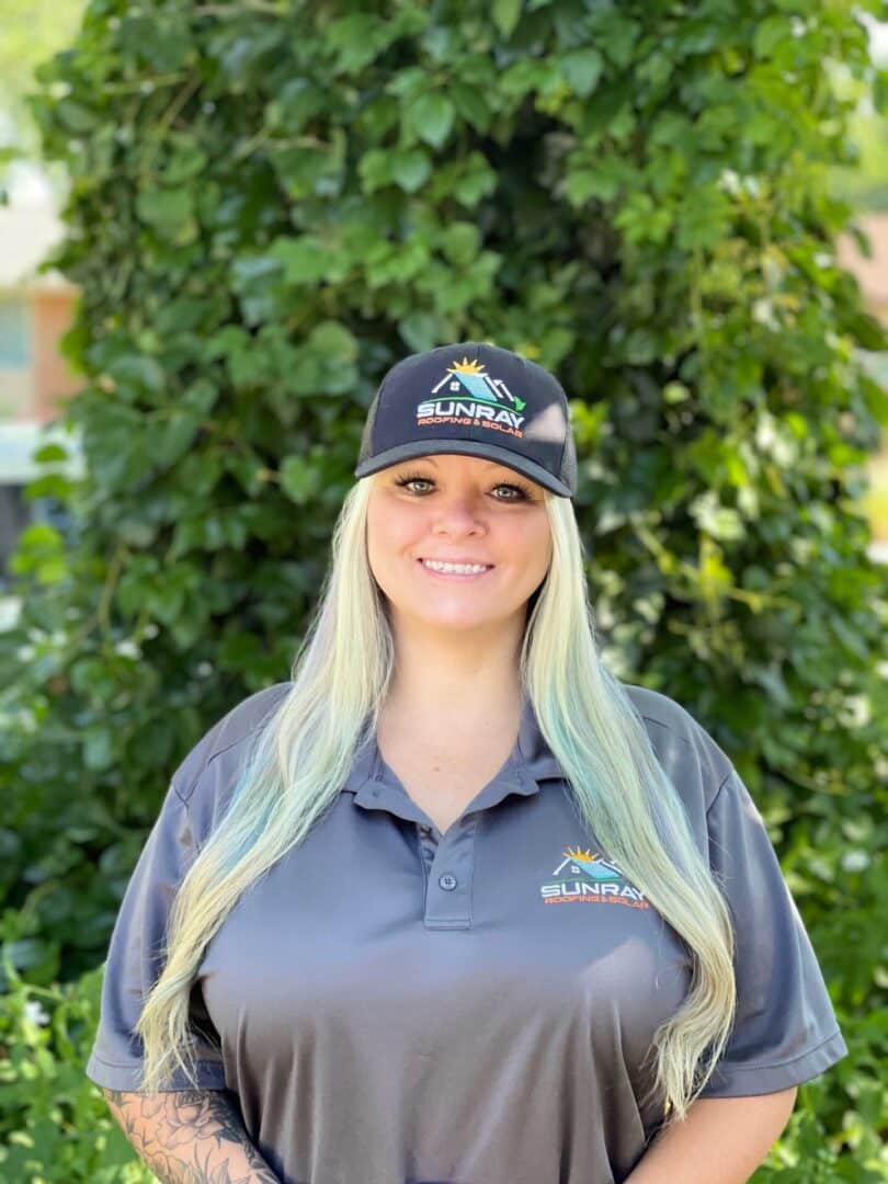 A woman standing in front of some bushes wearing a hat