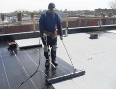 A man on top of a building with a hose.