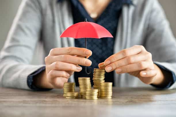 Hands protecting pile of coins with umbrella Young woman hands holding red umbrella over stacked coin on table. Female hand holding a small umbrella to protect heaps of coins while saving them. Financial security and savings protection concept. Financial Stability And Insurance stock pictures, royalty-free photos & images