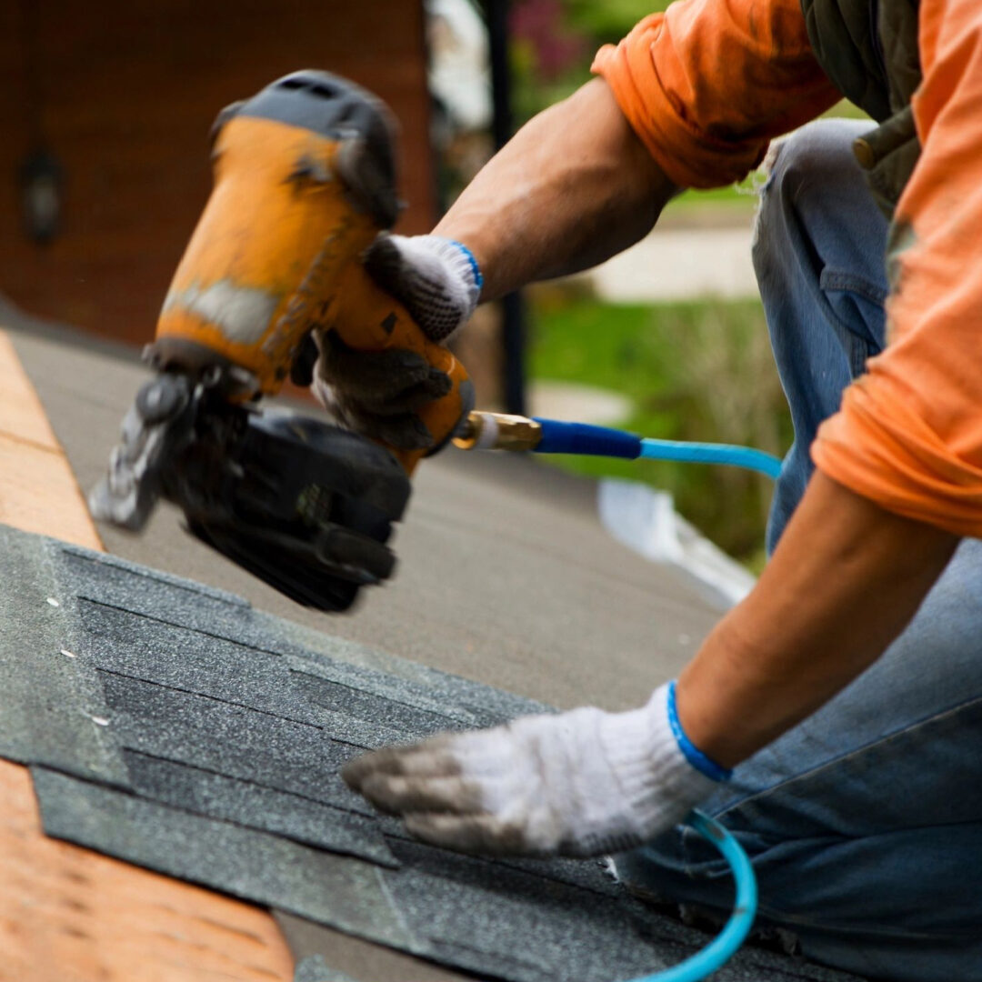 A person with a power tool on top of a roof.