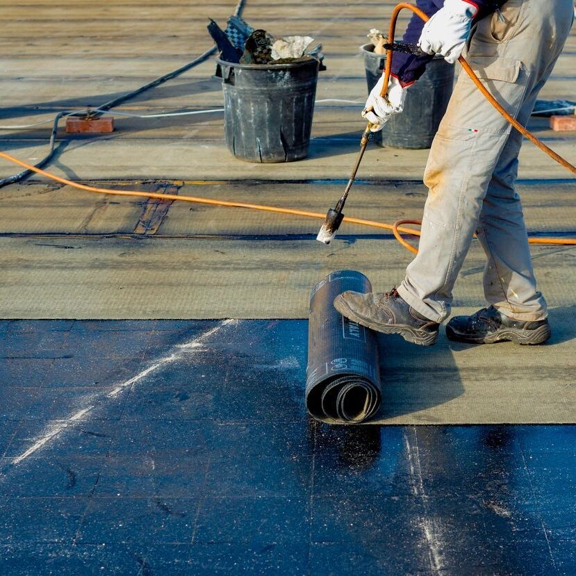 A man is painting the floor of a building.