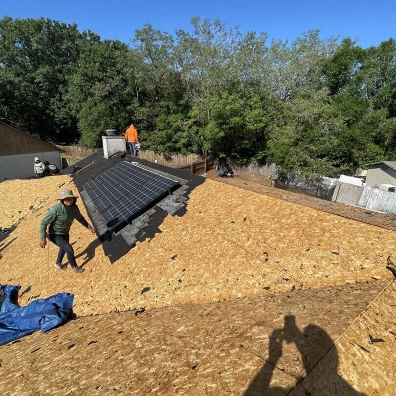 A man is holding the roof of a solar panel.